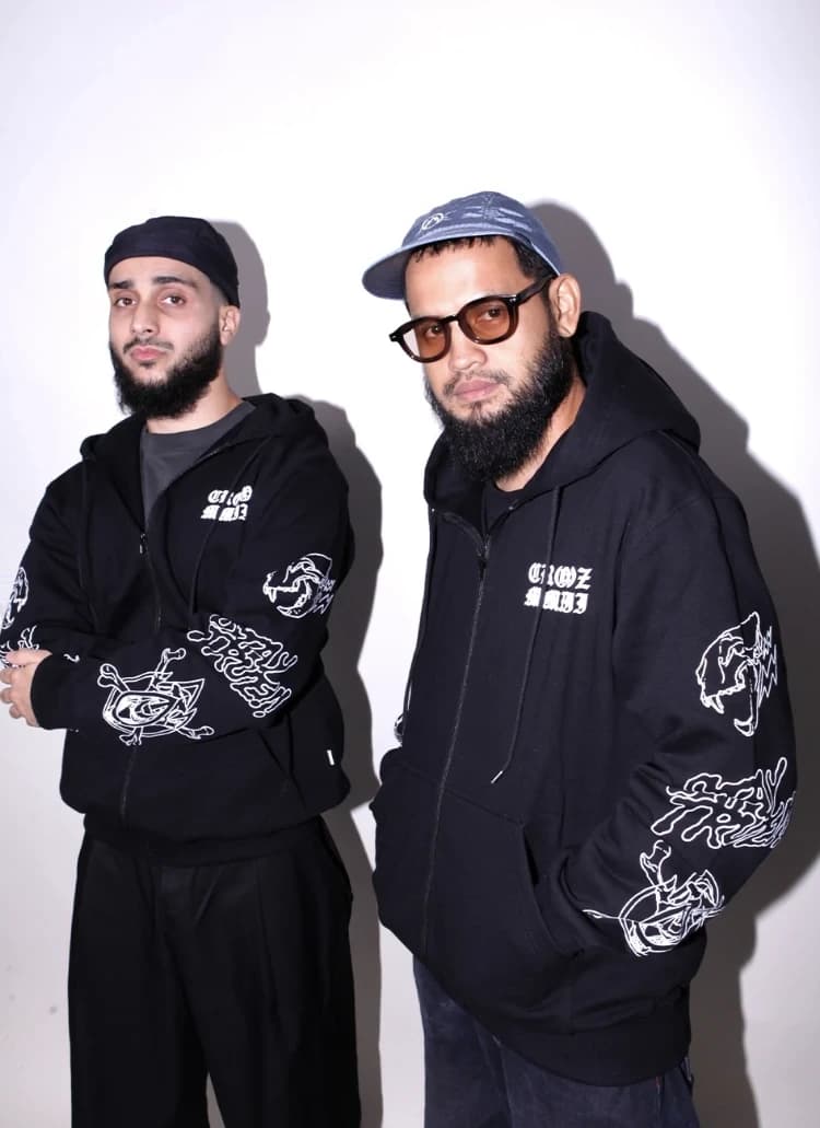 Dua model berdiri memakai hoodie hitam MMIII dengan sablon lengan