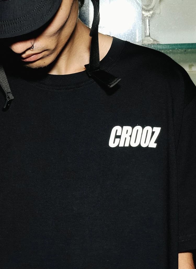Close-up logo CROOZ putih di dada kaos hitam