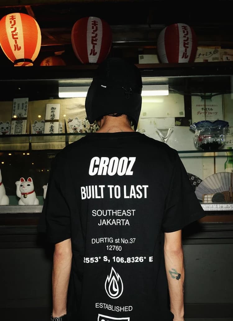 Punggung kaos Built to Last bertuliskan Southeast Jakarta, Durtig St. No. 37, 12760 dan koordinat, di depan etalase bar